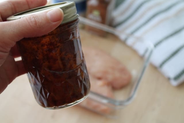 a hand shaking marinade in a glass jar
