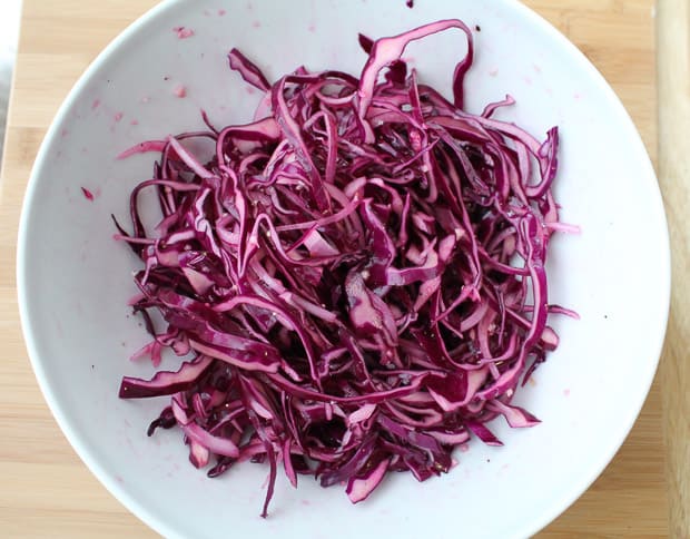tangy red cabbage slaw marinating in a mixing bowl