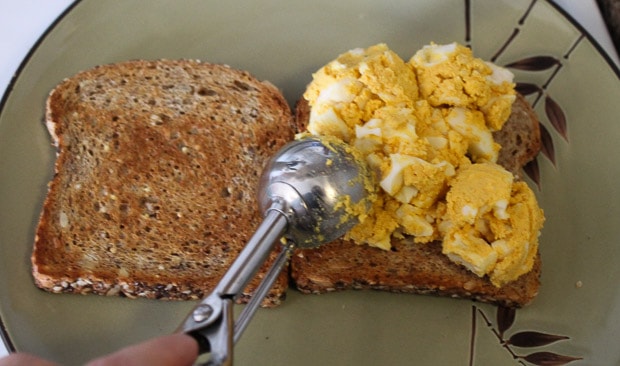 Egg salad being scooped onto bread