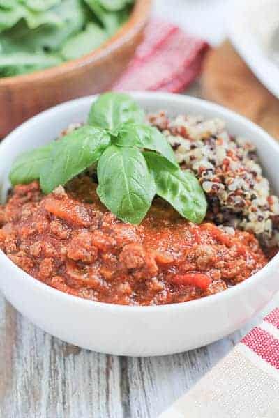 meal garnished with fresh basil and an arugula salad in a wooden bowl