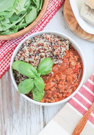 meal garnished with fresh basil and an arugula salad in a wooden bowl