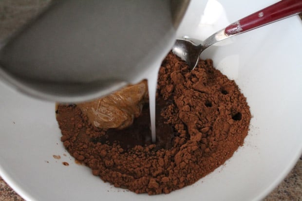 coconut oil being poured over cocoa powder and peanut butter