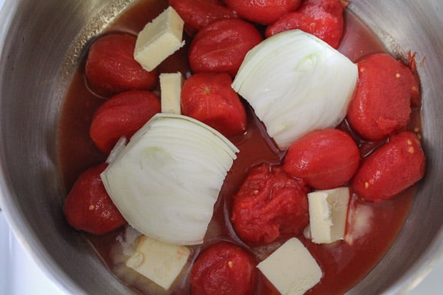 A Sauce pan with plum tomatoes, onion and butter