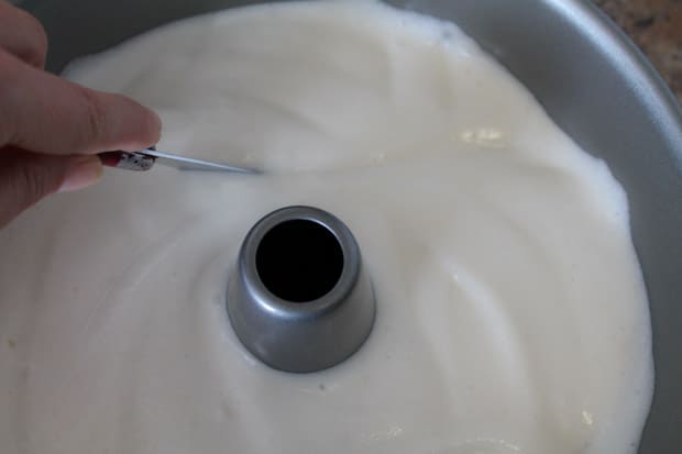 cake batter in a tube pan being sliced with a knife