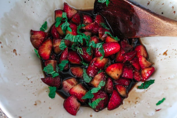 Fresh mint leaves being stirred into a bowl of berries.