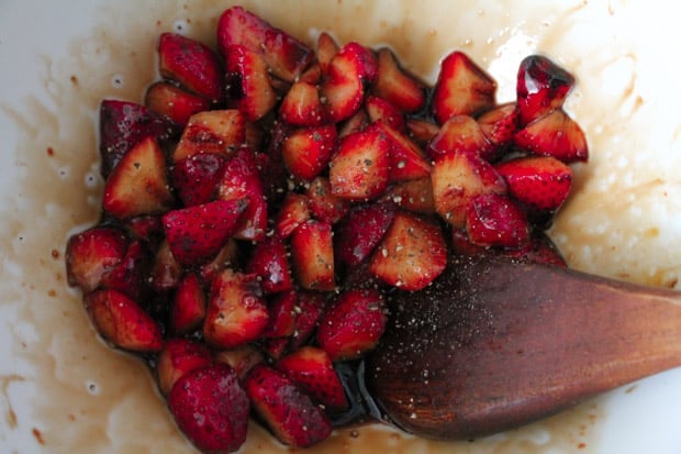 berries in a bowl being stirred with pepper and balsamic glaze.
