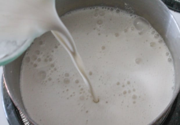 white creamy liquid being poured into a saucepan.