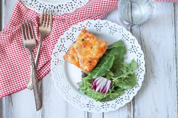 Cheesy casserole on a plate with salad.