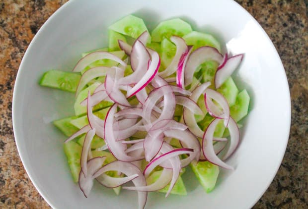 mixing bowl with sliced cucumbers and onions