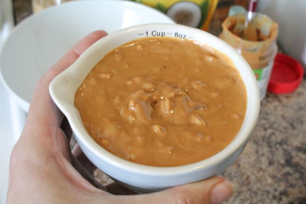 measuring cup with drippy, natural peanut butter inside
