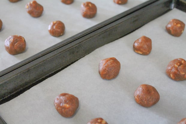 cookie dough rolled into balls on parchment lined baking sheets