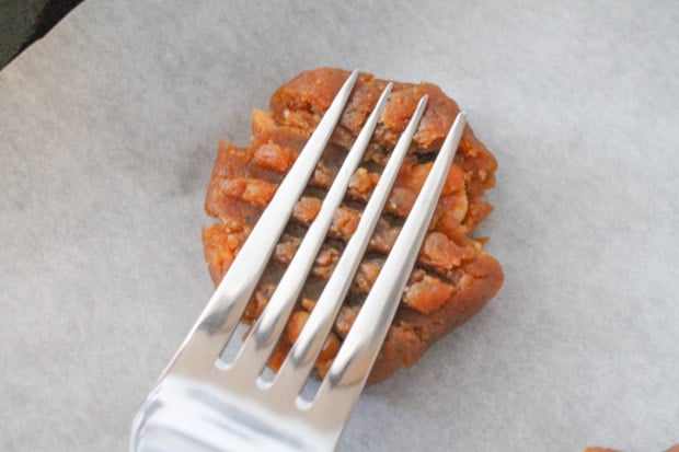 a fork pressing into a ball of cookie dough making a crisscross pattern