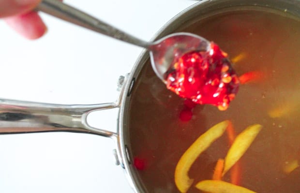 A spoon with spicy sauce about to be stirred into soup