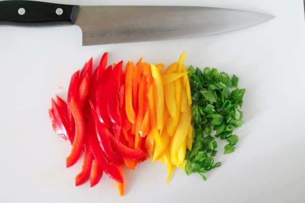 sliced peppers and green onions on white cutting board