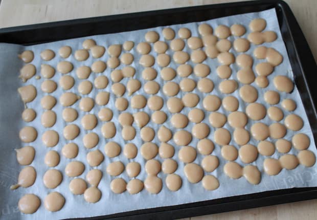 Peachy Frozen Yogurt Bites dotted out on a parchment lined baking tray