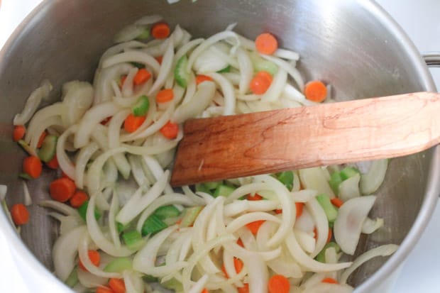 sliced onions and carrots in a soup pot