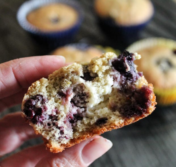 a hand holding a half eaten Lemon Berry Quinoa Flour Muffin