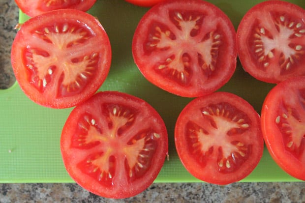 tomatoes cut in half on a green cutting board