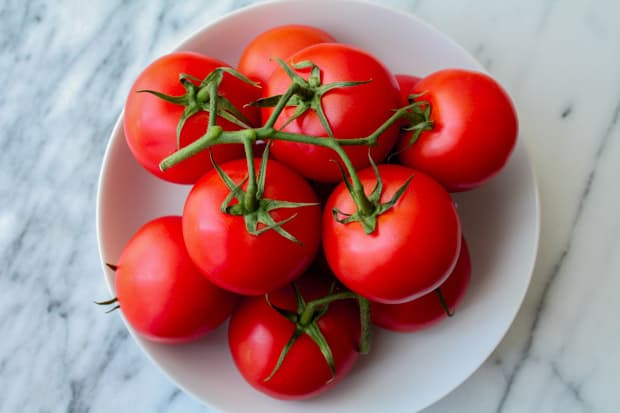 a white bowl full of red tomatoes