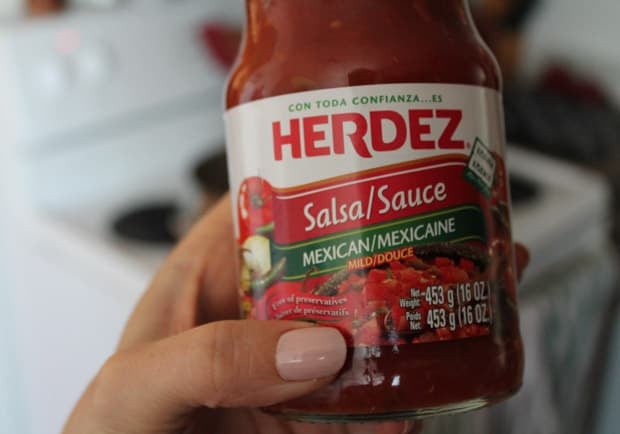 a hand holding a jar of Herdez brand salsa