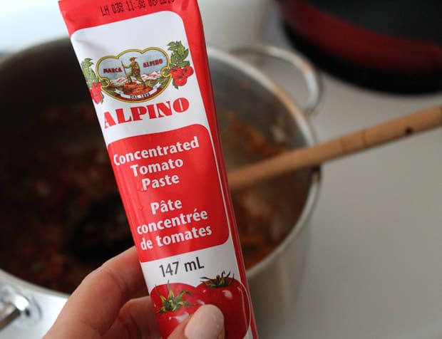 a hand holding a tube of tomato paste