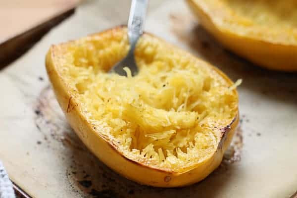 spaghetti squash fresh out of the oven being shredded with a fork