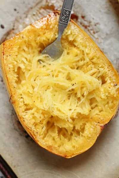 spaghetti squash fresh out the oven being shredded with a fork