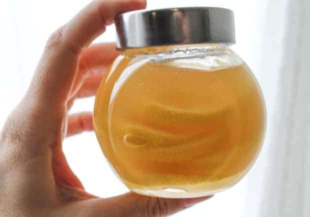 a hand holding a jar of Natural Honey Lemon Cold Remedy