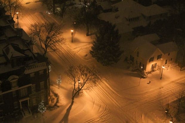 a snowy street with Christmas lights on trees