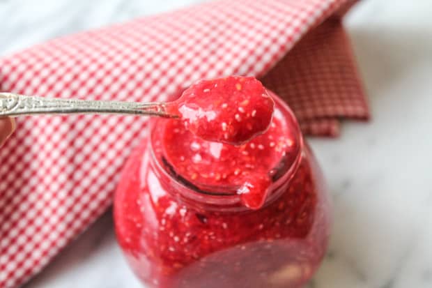 Raspberry chia seed jam being spooned out of a jar