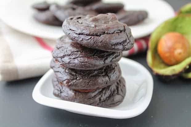 Fudgy Chocolate Avocado Cookies in a plate with a fresh sliced avocado in the background