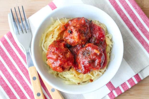 Oven Baked Turkey Meatballs in tomato sauce on a bed of spaghetti squash in a white bowl.