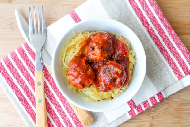 Oven Baked Turkey Meatballs in tomato sauce on a bed of spaghetti squash in a white bowl.