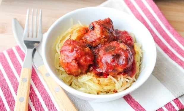 Oven Baked Turkey Meatballs in tomato sauce on a bed of spaghetti squash in a white bowl.