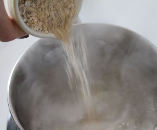 oat bran being poured into a pot of boiling water