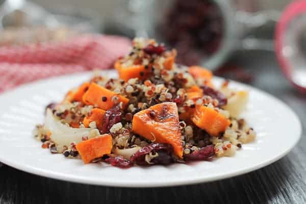 Spicy Roasted Butternut Squash with Quinoa & Cranberries on a white plate with a red checkered napkin in the background