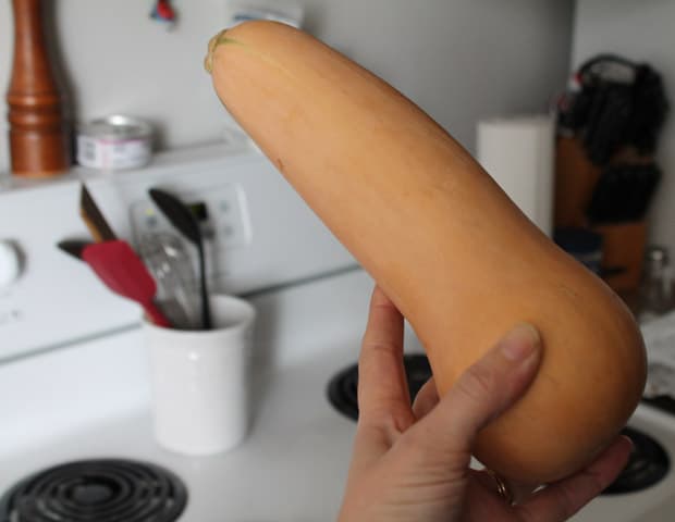 A hand holding a large butternut squash