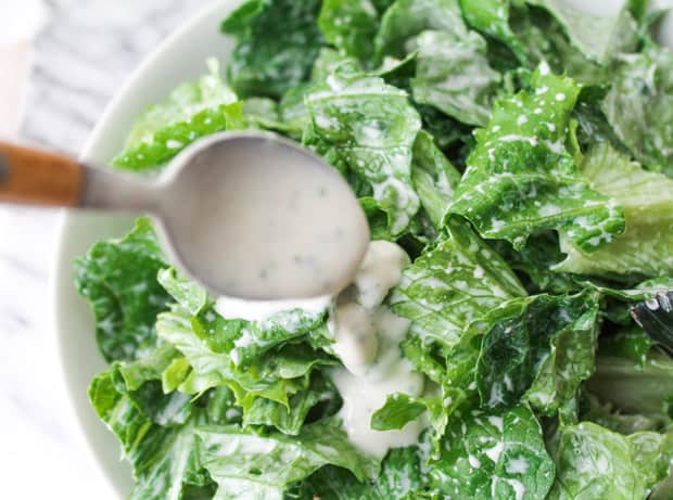 Ranch dressing being spooned onto a salad