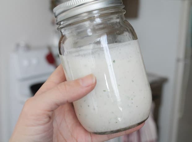 Homemade ranch dressing in a jar being held in a hand
