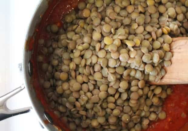 Lentils being stirred into sauce