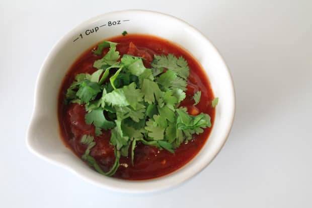 salsa in a dish with fresh chopped cilantro about to be stirred in