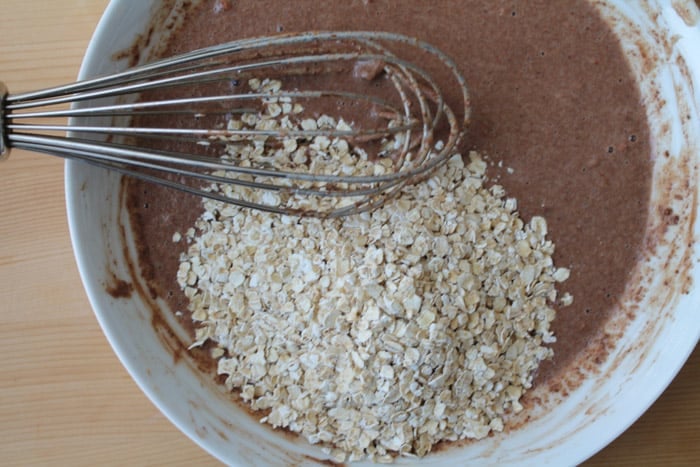 a whisk stirring oatmeal flakes into a chocolate mixture