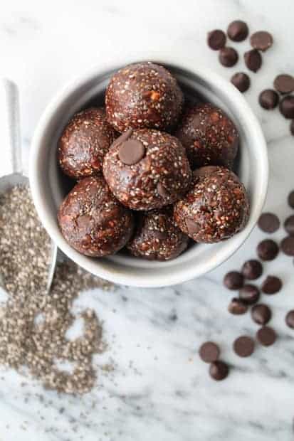  No Bake Chocolate Chia Power Balls on a white marble board with scattered chocolate chips in the background