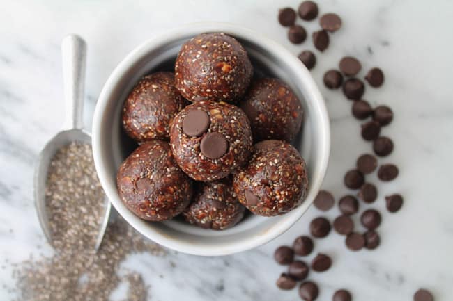 No Bake Chocolate Chia Power Balls on a white marble board with scattered chocolate chips in the background