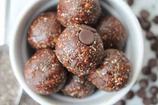 No Bake Chocolate Chia Power Balls on a white marble board with scattered chocolate chips in the background