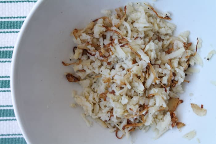 grated potato in a white mixing bowl.