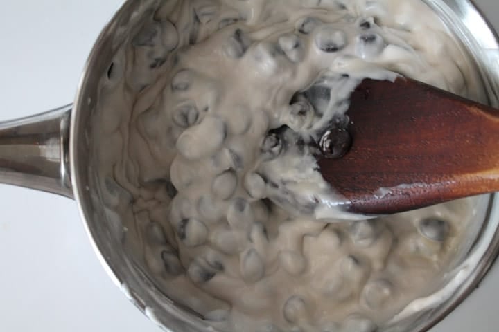 chocolate mixture in a saucepan being stirred by a wooden spoon