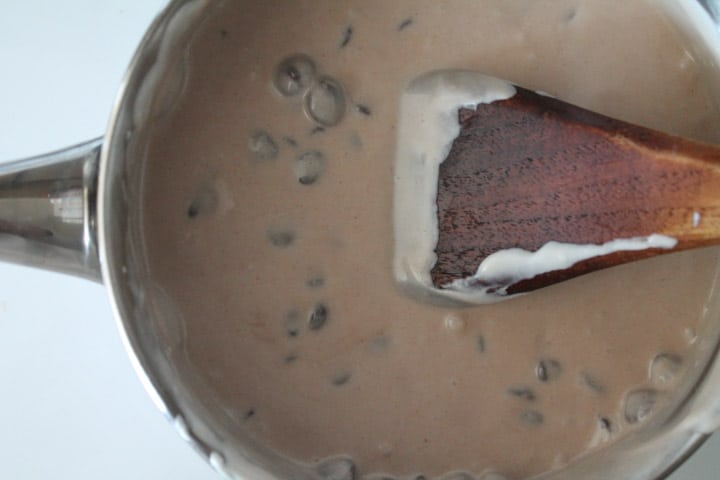 chocolate mixture in a saucepan being stirred by a wooden spoon