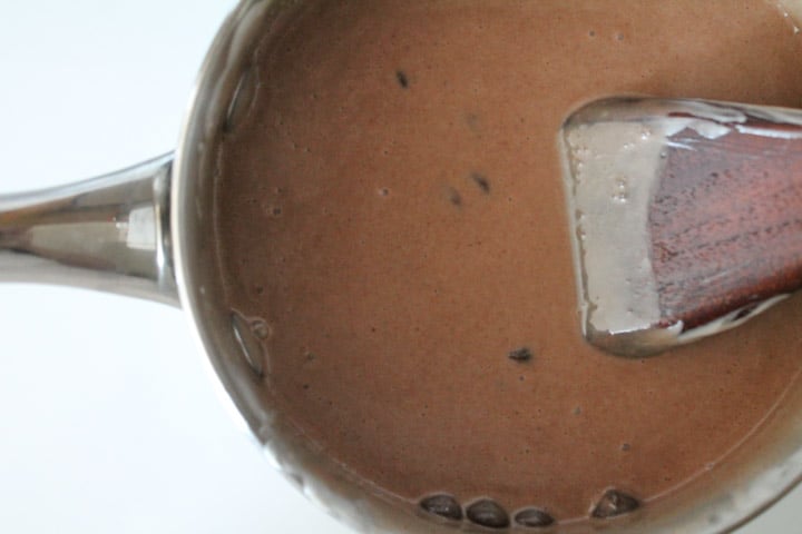 chocolate mixture in a saucepan being stirred by a wooden spoon