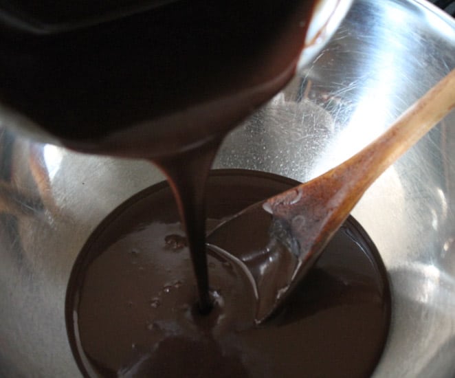 thick, chocolate being poured into a stainless steel mixing bowl